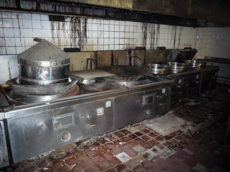 Large Chinese woks are placed on another end of the kitchen where food is prepared for all inmates 
