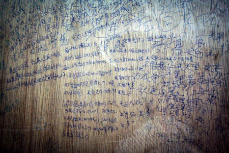 The bed boards are covered with writings by inmates