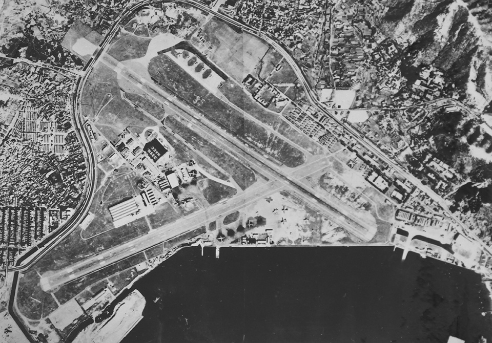 圖中左上角跨越馬路的方型空地便是07跑道橫跨清水灣道的伸延部份，機場中央夾在兩條跑道中間的黑色建築便是港機機庫。(1955年)
