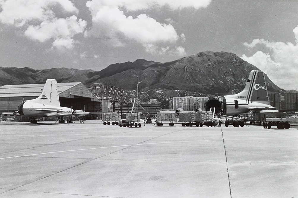 七十年代前啟德未建成空運貨站，港機機庫外的停機坪成為貨機上落貨的停機坪，遠處為新入伙的彩虹邨及興建中的坪石邨。