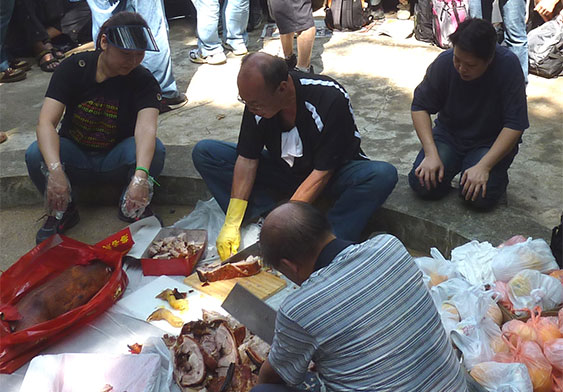 Ng Yiu Fai helping to cut a celebratory roast pig