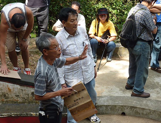 A clan official distributing money during the grave sweeping ceremony