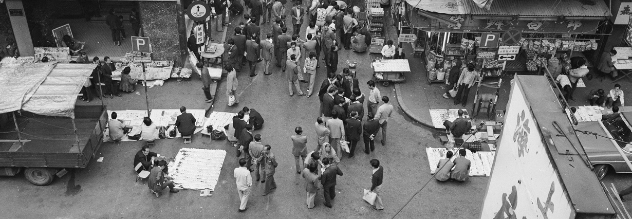 南京街左側為人人茶樓，右側路旁熟食檔是楊財發牛什粉麵檔。廣東道/南京街交界，1974年。
