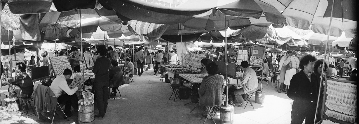 玉石市場，固定市場建築尚未建成，檔主均以太陽傘遮陰。1986年。